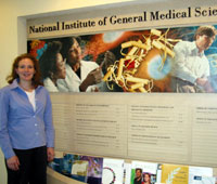 Alisa stands next a display that highlights many of the educational materials produced by her and others at the National Instiute of General Medical Sciences