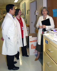 Elise Kohn, Virginia Kwitkowski and Edwin Posadas stand outside a patient’s room while they complete daily rounds on patients involved in their clinical trials.