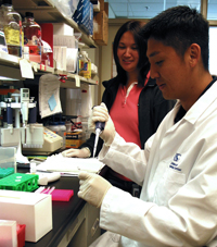 A colleague oversees Joel as he prepares DNA samples and is trained to use a new higher output genome sequencer.