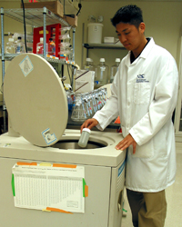 Joel loads bottled cell cultures into a centrifuge that spins at around 50,000 revolutions per minute.
