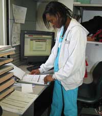 Kevilin reviews patient charts on paper and on the computerized patient database.